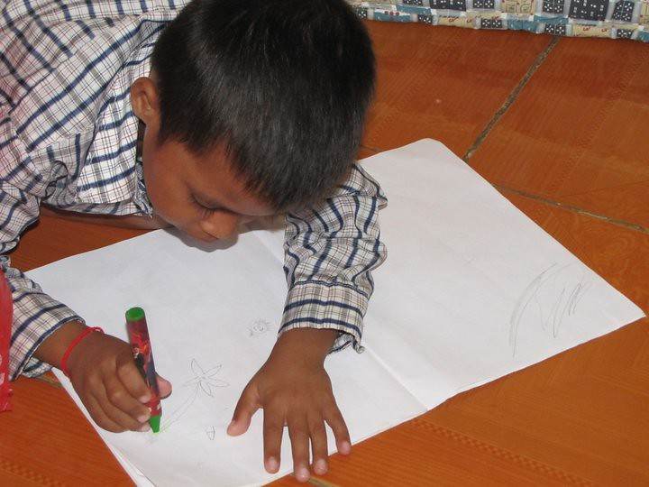 Boy drawing on paper on tiled floor with green marker