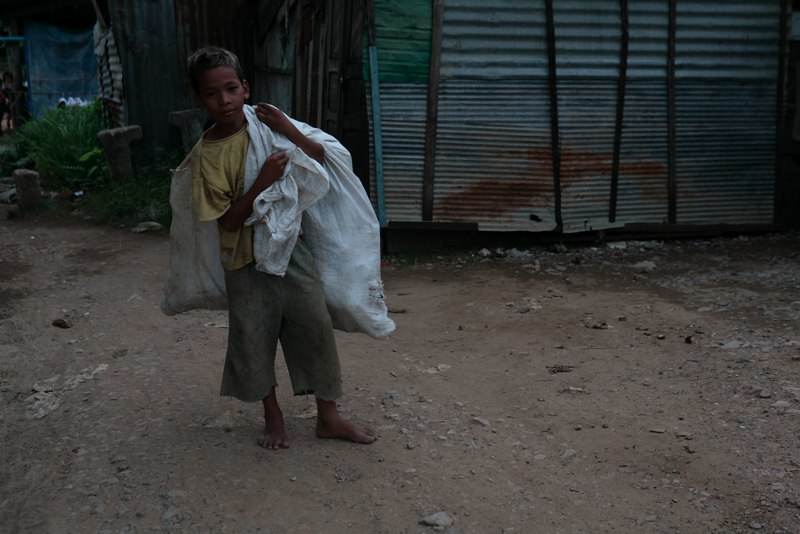 Boy carrying large white sack walking on dirt path