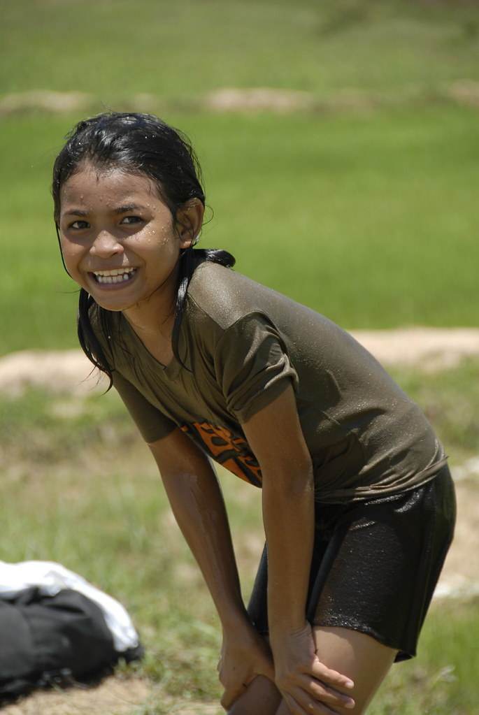 Girl covered in mud smiling in rice paddy