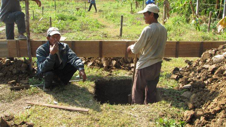 Two men working at construction site near dug hole
