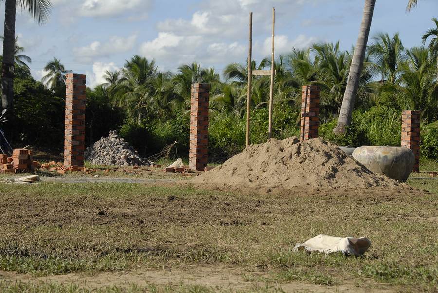 Brick pillars and sand pile at construction site with palm trees