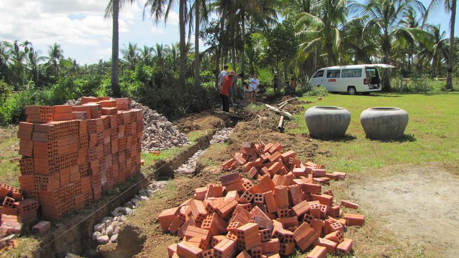 Workers digging trench with brick piles and water jars