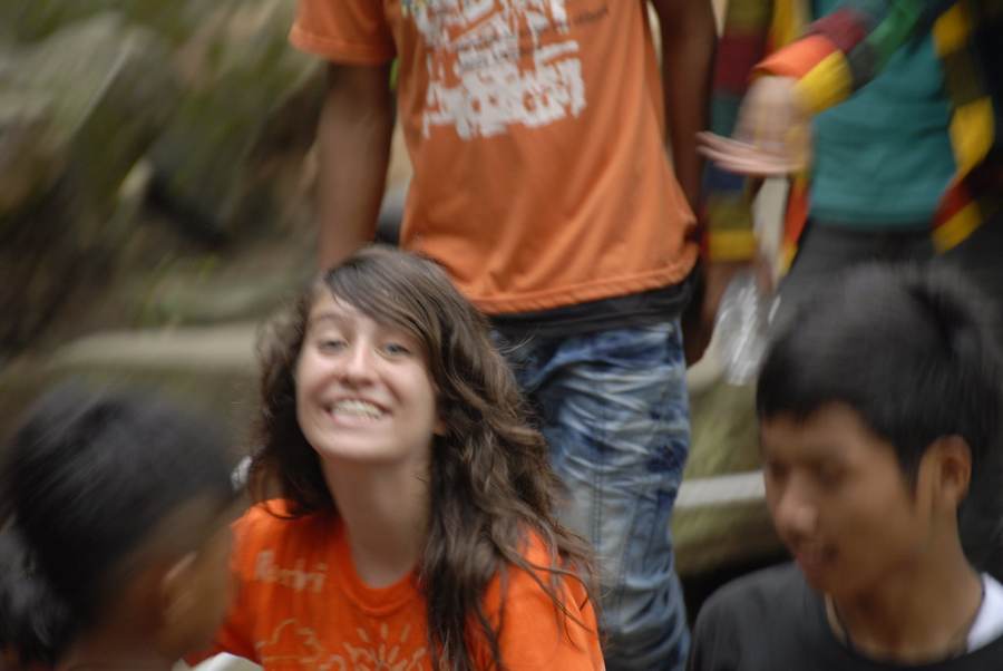 Young woman in orange shirt smiling among group