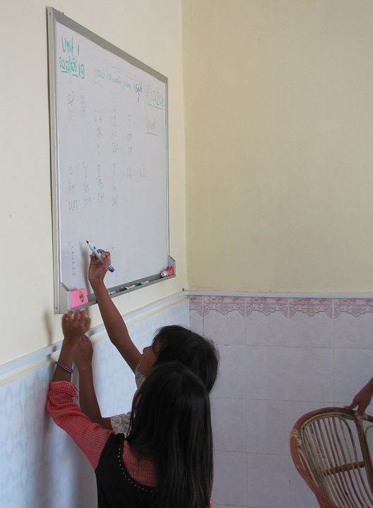 Students writing on whiteboard in classroom