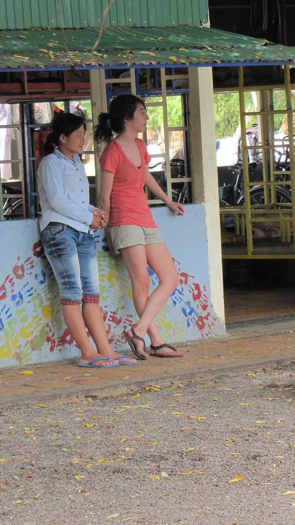 Two women leaning against colorful painted wall