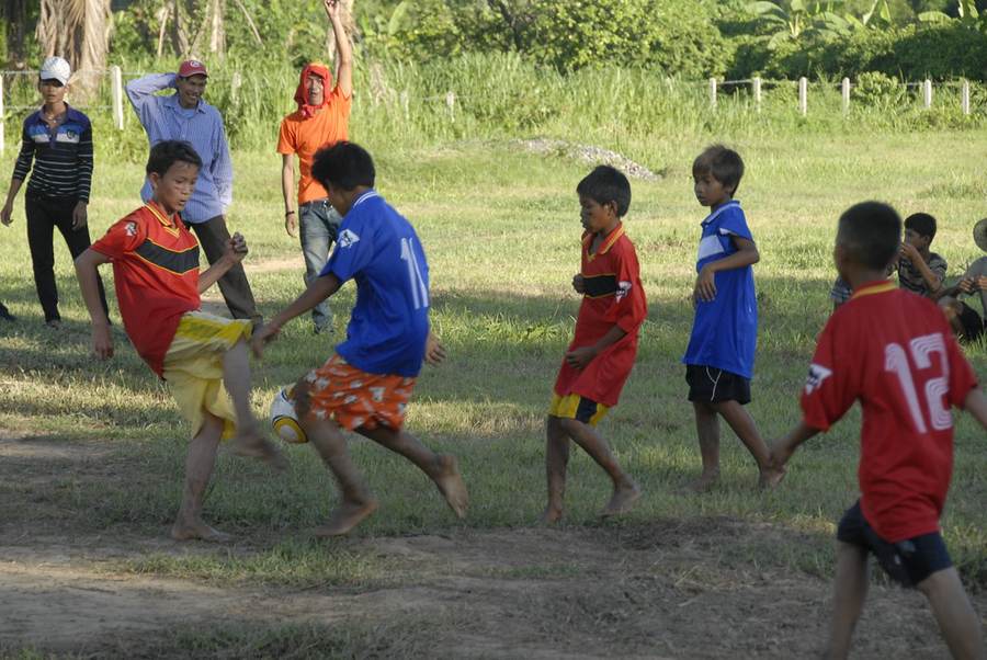 Children playing soccer with adults watching