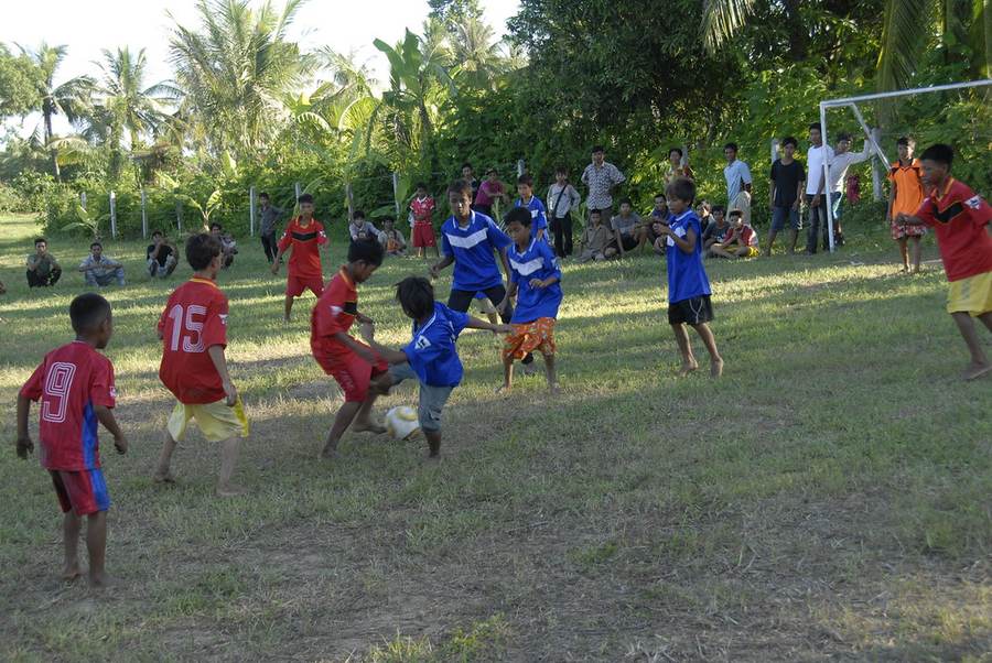 Wide shot of children playing soccer with spectators