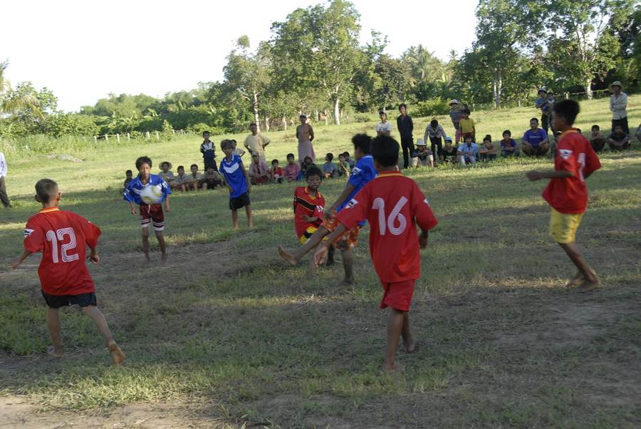 Children playing soccer with spectators on grass field