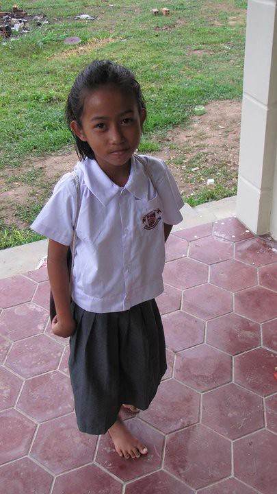 Young girl in white school uniform standing on hexagonal tile floor