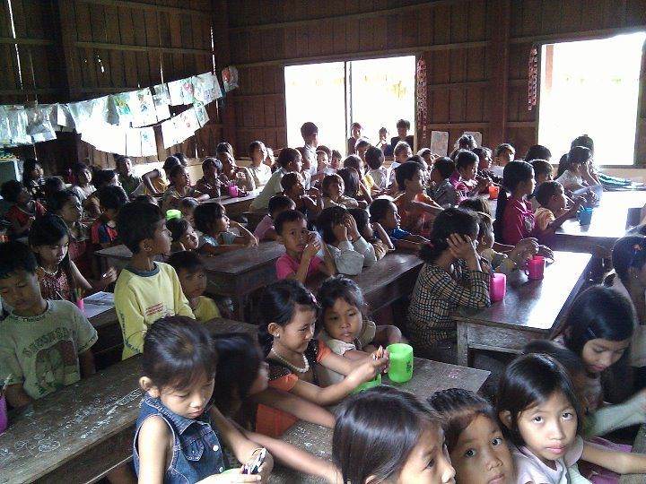 Large classroom full of students at desks with green cups