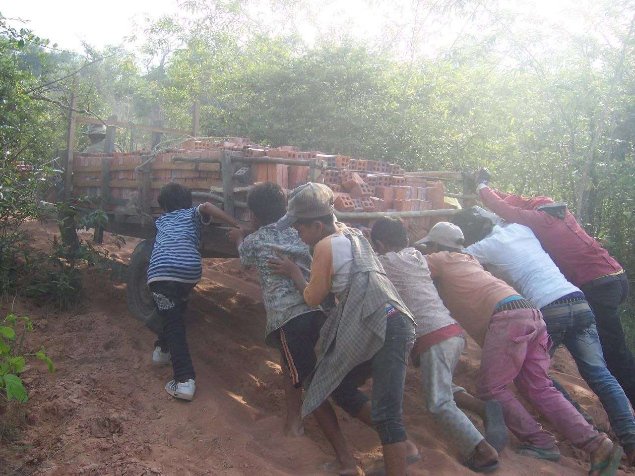 Community members pushing a brick cart through rural Cambodia